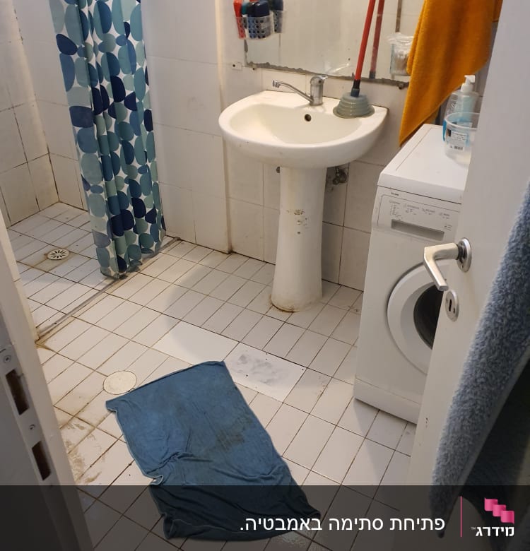 חדר אמבטיה עם כיור, פומפה ומגבת על הרצפה